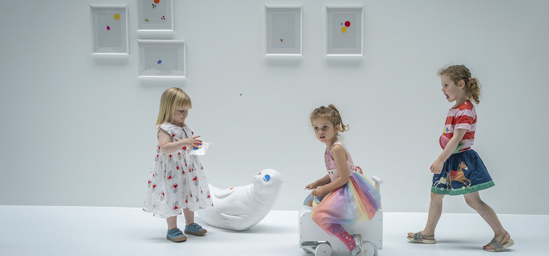 Los niños colocan las primeras pegatinas en la obra interactiva de Yayoi Kusama The obliteration room, que comienza como un apartamento blanco lleno de muebles blancos, que los visitantes están invitados a cubrir con pegatinas, en la Tate Modern de Londres, el viernes 22 de julio de 2022.
