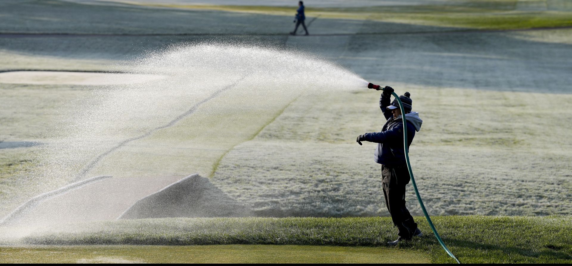 Un jardinero riega el campo durante una helada antes de la primera ronda del torneo de golf PGA Championship en Oak Hill Country Club el jueves 18 de mayo de 2023 en Pittsford, Nueva York (AP Photo/Seth Wenig)