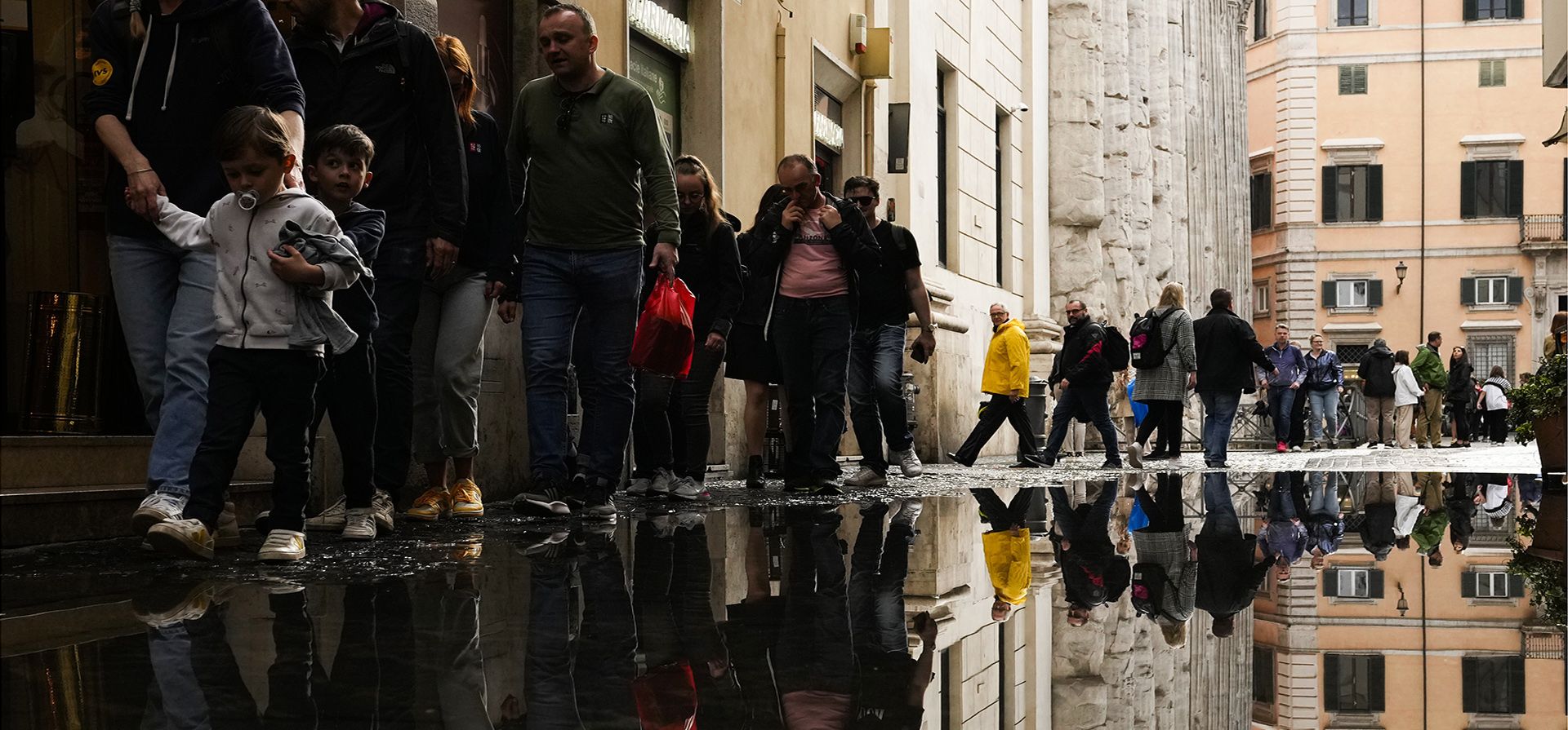 Personas se ven reflejadas en un charco después de fuertes lluvias en el centro de Roma, el miércoles 3 de mayo de 2023. (Foto AP/Alessandra Tarantino)