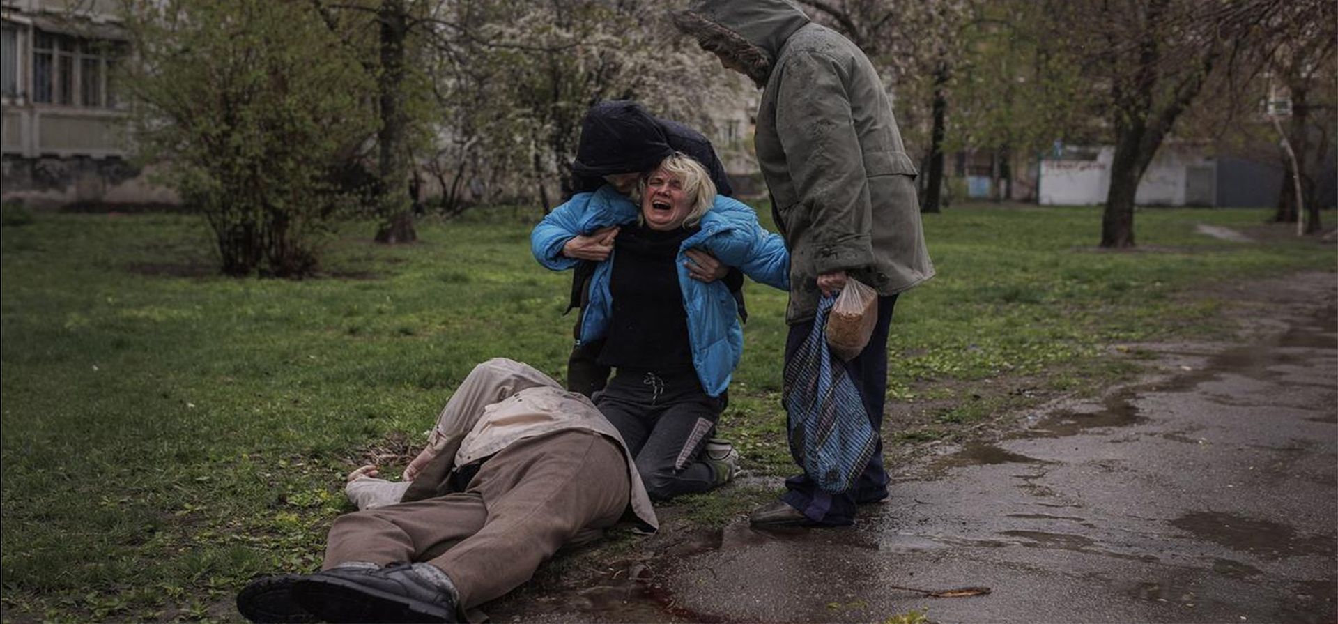 Fotografía de Alkis Konstantinidis para Reuters. Yana Bachek (centro), consolada por su pareja Yevgeniy Vlasenko y su madre Lyubov lloran sobre el cuerpo de su padre Victor Gubarev (79), asesinado mientras compraba pan durante el bombardeo de Kharkiv, Ucrania, el 18 de abril de 2022. Región de Europa. /World Press Photo 2023