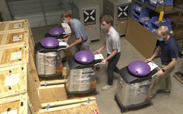 Trabajadores cargan LightStrike, el primer robot matador de coronavirus probado en el mundo, en cajas de envío. Debido a la demanda mundial, Xenex anuncia que está aumentando la fabricación de dispositivos de desinfección por rayos UV de xenón que eliminan los gérmenes.