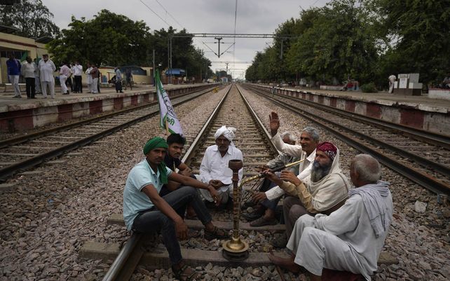 Agricultores que protestan contra las polémicas leyes agrícolas gritan consignas sentados en las vías del tren mientras bloquean trenes durante seis horas en Bahadur Garh, en las afueras de Nueva Delhi, India, el lunes 18 de octubre de 2021.
