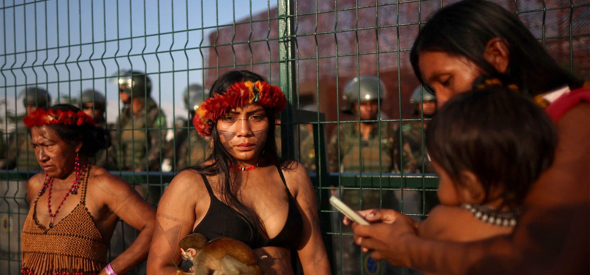 Una mujer Munduruku sostiene un mono ardilla mientras bloquea el acceso a la COP30, la conferencia de la ONU sobre el cambio climático, con otros pueblos indígenas mientras los soldados brasileños montan guardia, Belém, Brasil. Fotografía: Adriano Machado/Reuters Una mujer Munduruku sostiene un mono ardilla mientras bloquea el acceso a la COP30, la conferencia de la ONU sobre el cambio climático, con otros pueblos indígenas mientras los soldados brasileños montan guardia, Belém, Brasil. Fotografía: Adriano Machado/Reuters