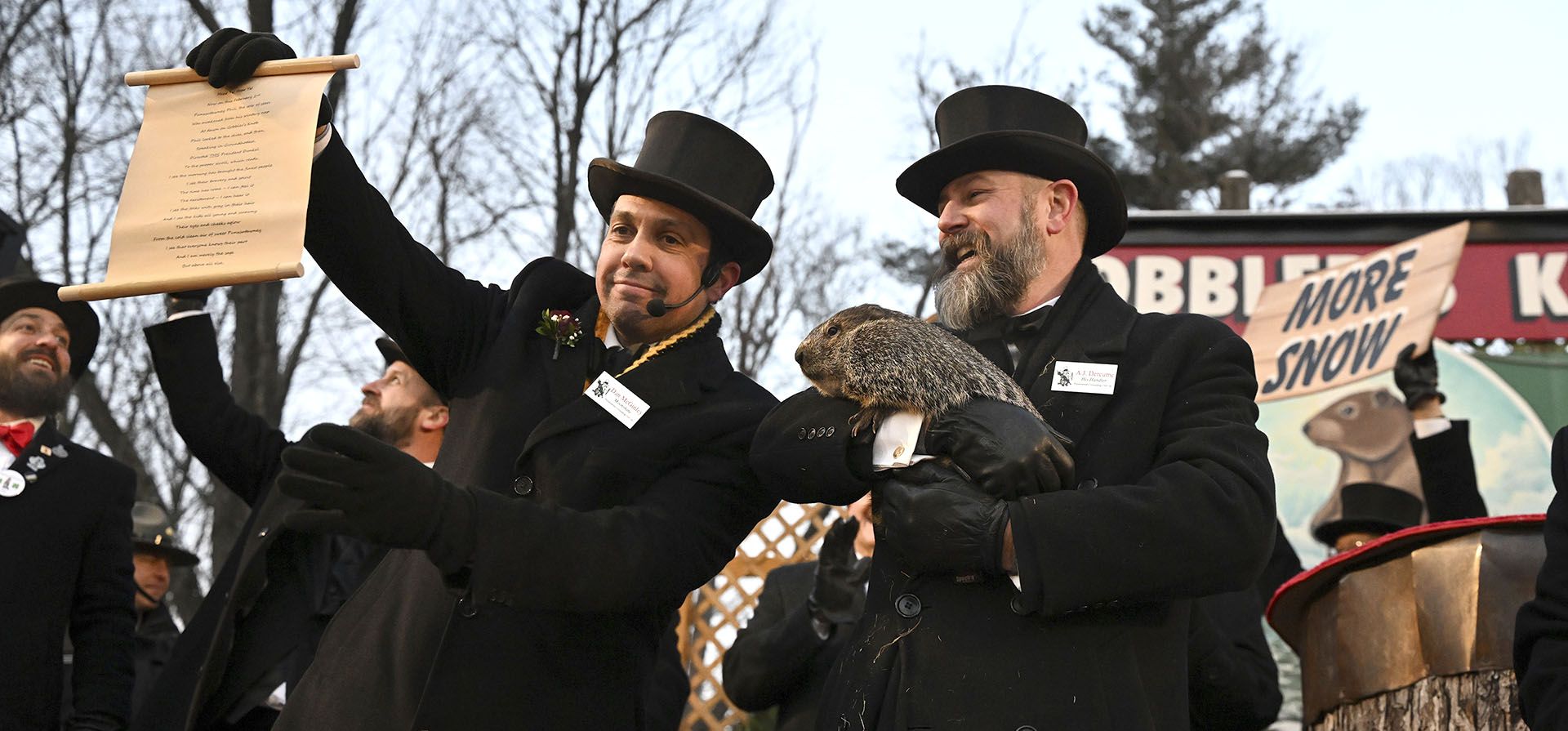 El manejador del Groundhog Club A.J. Dereume, sostiene a Punxsutawney Phil, la marmota que pronostica el clima, mientras que el vicepresidente Dan McGinley lee el pergamino durante la celebración número 137 del Día de la Marmota en Gobbler