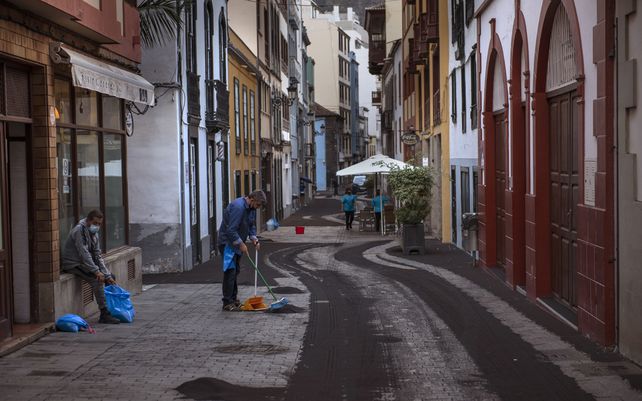 Residentes limpian la ceniza de una calle en Santa Cruz de la Palma en la isla canaria de La Palma, España, el lunes 27 de septiembre de 2021. Una enorme nube de ceniza impidió los vuelos dentro y fuera de la isla española de La Palma.