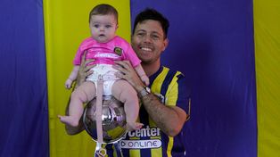 El papá posa orgulloso junto a su beba, sobre la Copa de la Liga que ganó el equipo de Russo.