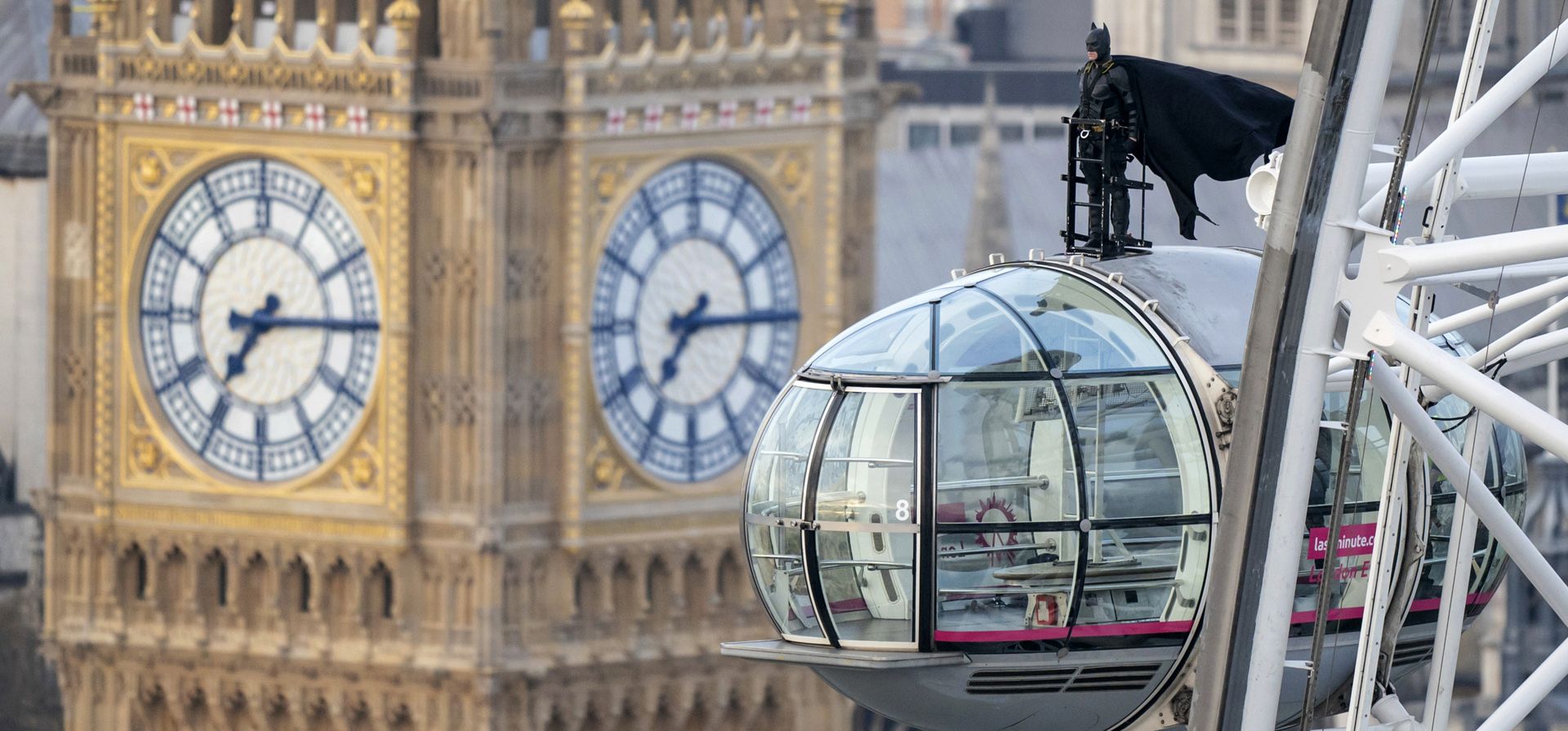 Un hombre vestido como el superhéroe Batman se para en la parte superior de una cápsula en el London Eye, la atracción turística más importante del centro de Londres, con el Big Ben de fondo, antes del estreno de The Batman en los cines de Gran Bretaña el 4 de marzo.