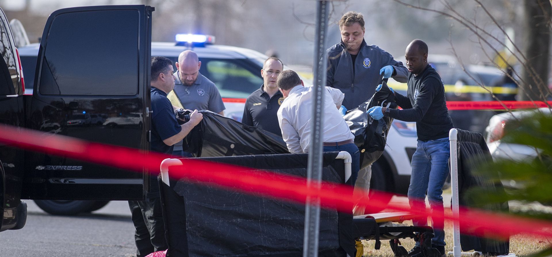 Agentes del alguacil de la parroquia de Jefferson y el personal forense levantan la bolsa para cadáveres que sostiene a un estudiante de la escuela secundaria John Ehret que recibió un disparo mortal cerca de una parada de autobús en Marrero, Luisiana.
