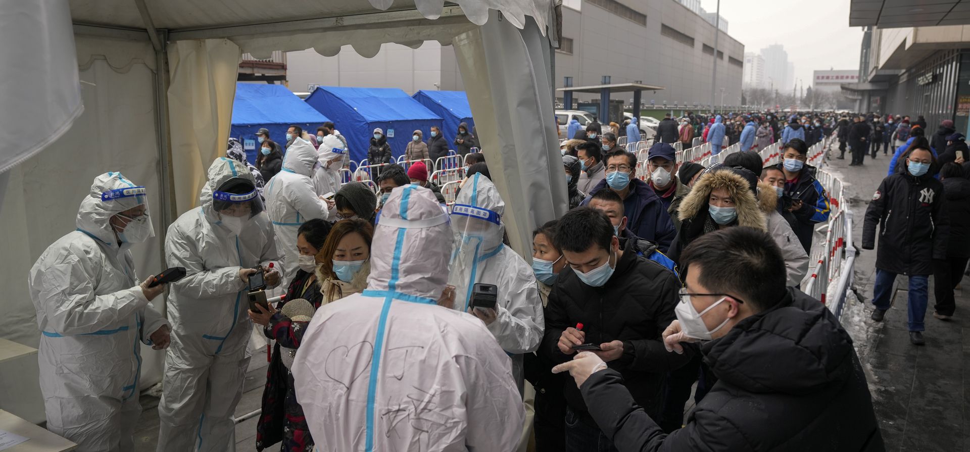 Trabajadores médicos escanean códigos en los teléfonos inteligentes de las personas en un sitio de pruebas masivas de coronavirus en Beijing, el lunes 24 de enero de 2022. Las autoridades chinas levantaron un bloqueo de un mes en Xi