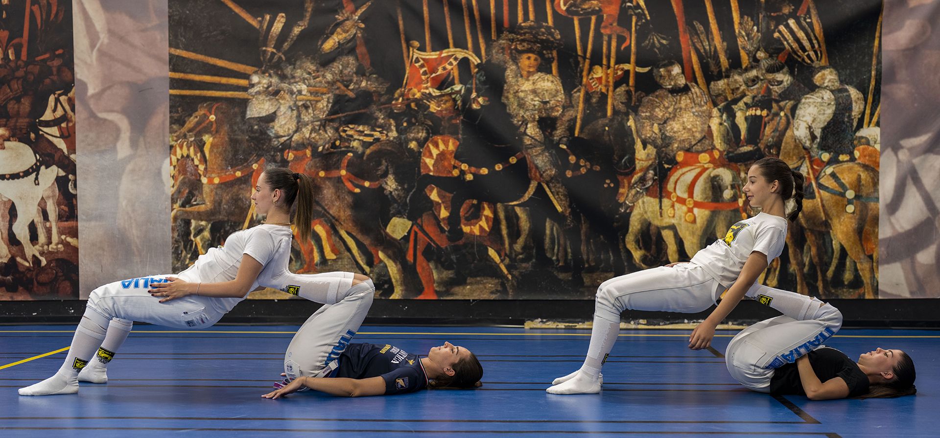 Jóvenes esgrimistas, elongan frente a una reproducción gigante de la obra maestra del pintor renacentista italiano Paolo Uccello, La batalla de San Romano, durante una sesión de entrenamiento con la Academia de Armas Musumeci Greco en Roma, el jueves 20 de junio de 2024. (Foto AP/Domenico Stinellis) Jóvenes esgrimistas, elongan frente a una reproducción gigante de la obra maestra del pintor renacentista italiano Paolo Uccello, La batalla de San Romano, durante una sesión de entrenamiento con la Academia de Armas Musumeci Greco en Roma, el jueves 20 de junio de 2024. (Foto AP/Domenico Stinellis)