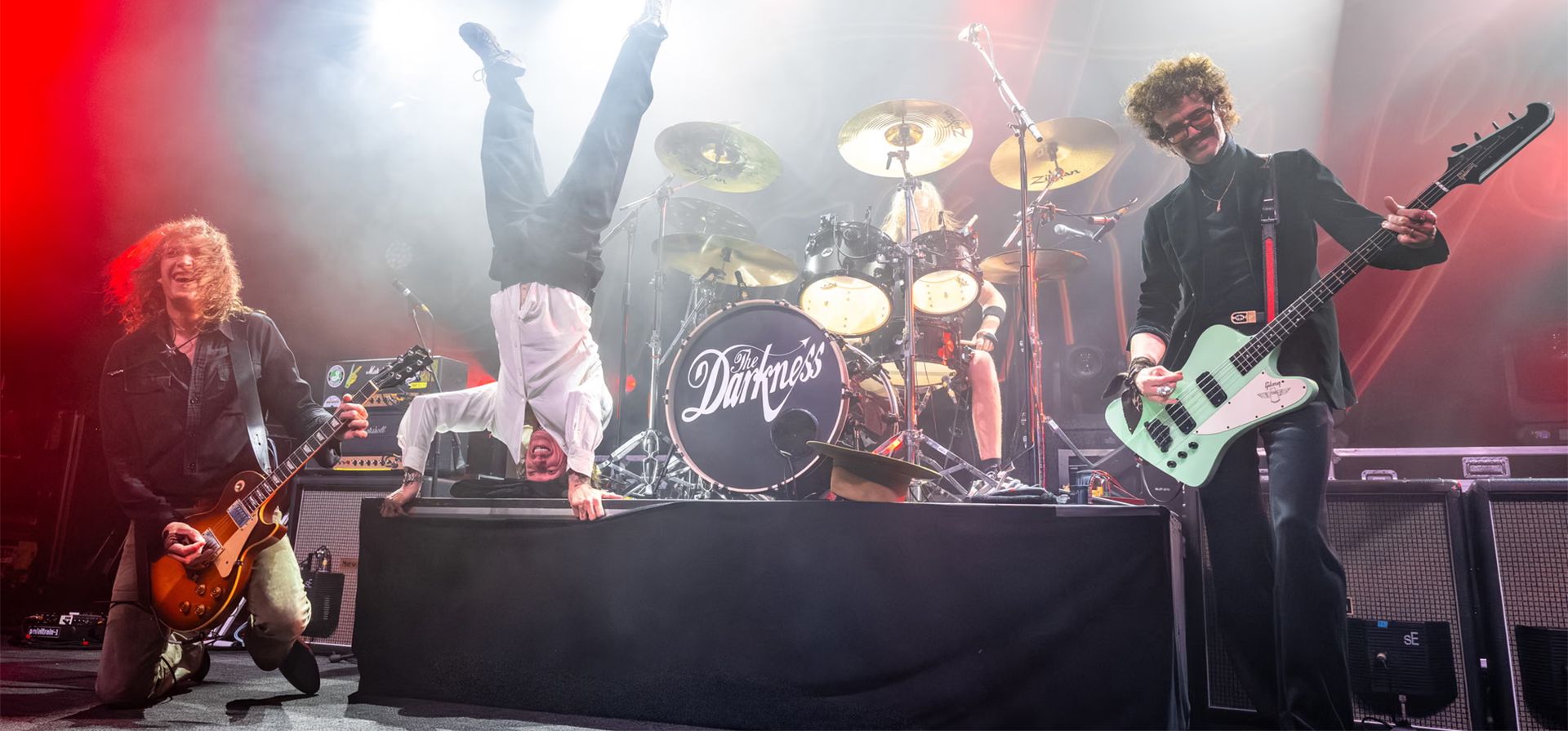 Justin Hawkins de The Darkness hace una parada de cabeza en el escenario mientras actúa con su hermano Dan Hawkins, a la izquierda, y Frankie Poullain en el Fillmore, San Francisco, Estados Unidos. Fotografía: Steve Jennings/Getty Images Justin Hawkins de The Darkness hace una parada de cabeza en el escenario mientras actúa con su hermano Dan Hawkins, a la izquierda, y Frankie Poullain en el Fillmore, San Francisco, Estados Unidos. Fotografía: Steve Jennings/Getty Images