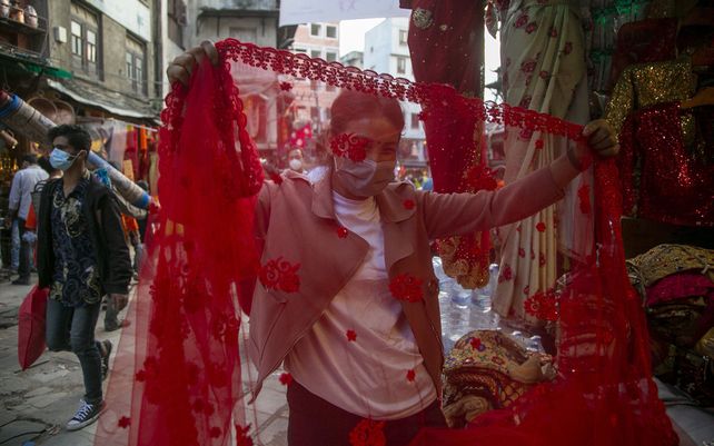 Una mujer nepalesa revisa un sari mientras realiza la compra en el primer día del festival Dashain en Katmandú, Nepal, el jueves 7 de octubre de 2021. El festival de diez días conmemora la victoria de los dioses sobre los demonios.