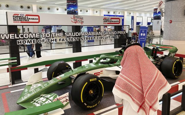 Un pasajero saudita observa un auto de carreras que anuncia la Fórmula Uno