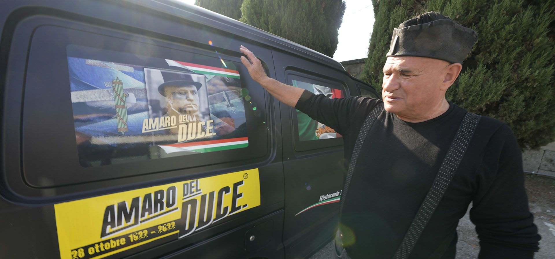 Un hombre muestra el saludo romano frente a un automóvil adornado con pegatinas que dicen Amaro (Licor) del Duce, en una marcha sobre Roma, con motivo del centenario del dictador fascista Benito Mussolini, en Predappio, el viernes 28 de octubre. 