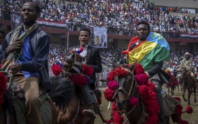 Jinetes actúan en el campo mientras los seguidores llenan las gradas en el mitin de campaña final del primer ministro de Etiopía, Abiy Ahmed, visto en una pancarta, en la ciudad de Jimma, en la región de Oromia, al suroeste de Etiopía.