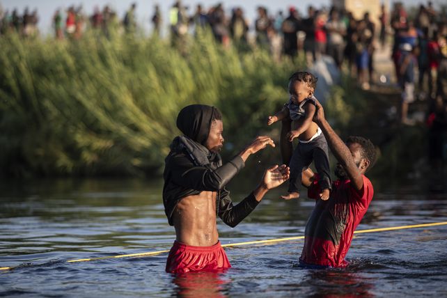 Haitians cross the river with a child.  Similar dramatic scenes have been repeated for weeks.