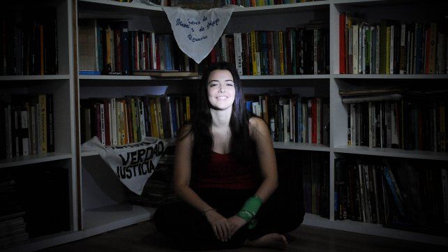 Lucía junto a los libros y banderas de su biblioteca.