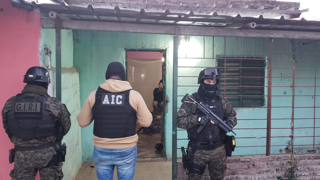 Efectivos policiales montan guardia en uno de las casas allanadas en Las Flores.