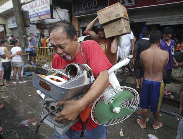 saqueos. Un filipino sale cargado de un negocio de electrodomésticos.