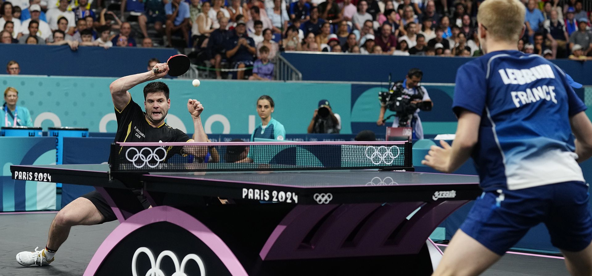 El alemán Dimitrij Ovtcharov, al fondo, juega contra el francés Felix Lebrun durante un partido de octavos de final de tenis de mesa individual femenino en los Juegos Olímpicos de Verano de 2024, el miércoles 31 de julio de 2024, en París, Francia. (Foto AP/Petros Giannakouris) El alemán Dimitrij Ovtcharov, al fondo, juega contra el francés Felix Lebrun durante un partido de octavos de final de tenis de mesa individual femenino en los Juegos Olímpicos de Verano de 2024, el miércoles 31 de julio de 2024, en París, Francia. (Foto AP/Petros Giannakouris)