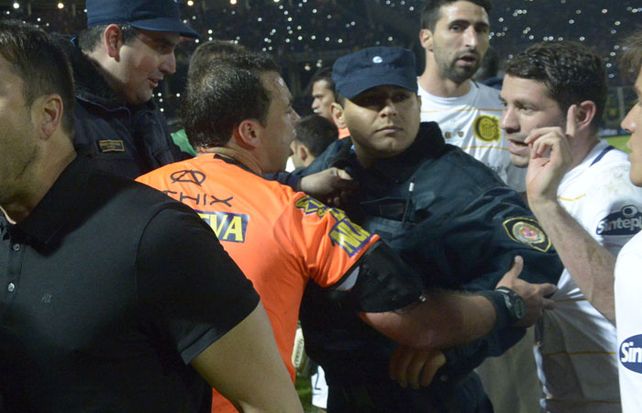 El árbitro Diego Ceballos es retirado por la policía mientras intenta darle explicaciones a José Luis Fernández. (Foto: S. Suárez Meccia)