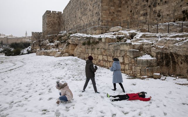Gente juega en la nieve en un parque junto a las murallas de la Ciudad Vieja de Jerusalén. Los sitios religiosos más sagrados de la ciudad amanecieron como pocas veces se los ha visto.