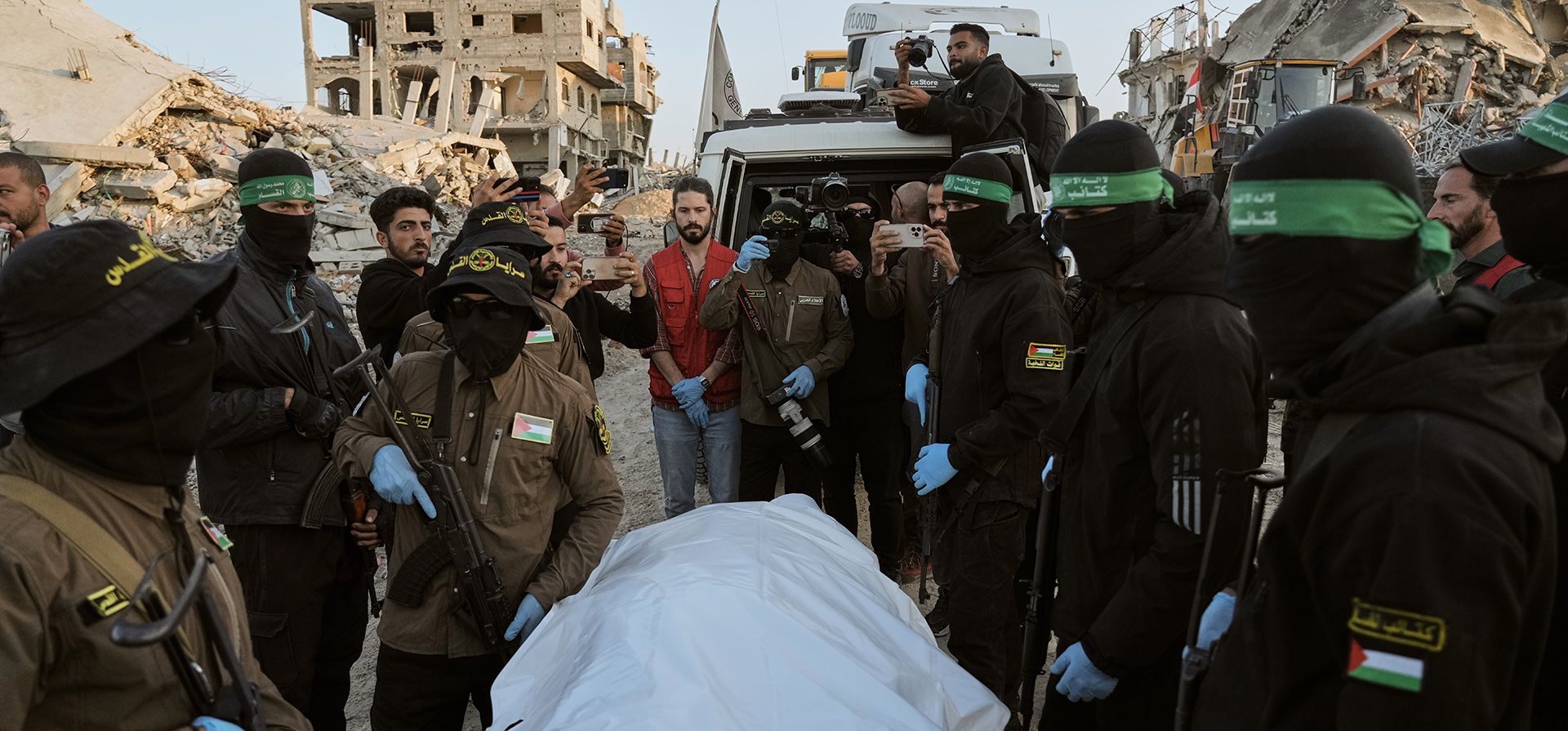 Militantes de la Yihad Islámica y Hamás entregan una bolsa para cadáveres que se cree contiene los restos de un rehén fallecido, a la Cruz Roja para su traslado a las autoridades israelíes, en Beit Lahiya, en el norte de la Franja de Gaza, el miércoles 3 de diciembre de 2025. (Foto AP/Jehad Alshrafi)