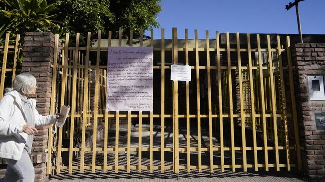 Dos carteles en la reja de entrada a la escuela, que cerró este lunes por duelo.