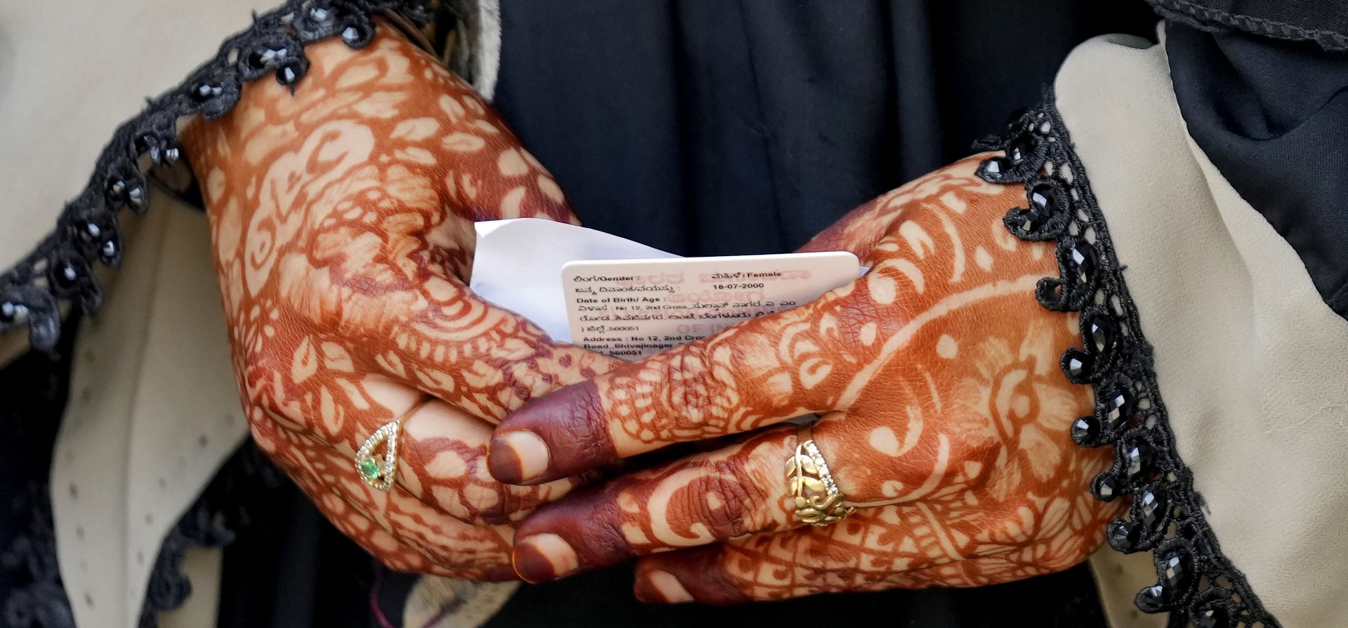 Una mujer con las manos decoradas con henna sostiene su credencial de elector mientras espera para emitir su voto en un centro de votación en Bangalore, India, el miércoles 10 de mayo de 2023. (Foto AP/Aijaz Rahi)