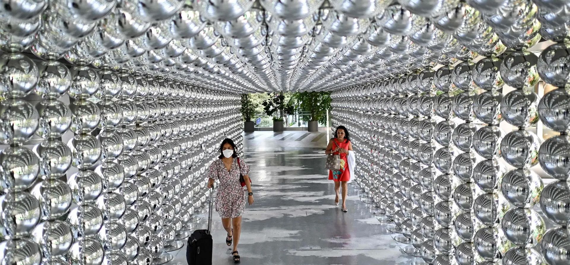 Bangkok, Tailandia. La gente camina a través de un túnel decorado con bolas reflectantes fuera de un centro comercial. Fotografía: Manan Vatsyayana/AFP/Getty Images