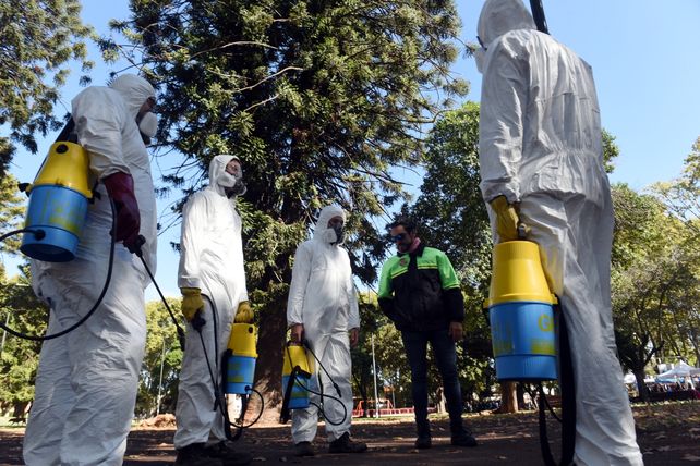 Agentes sanitarios municipales se preparan para fumigar una plaza.
