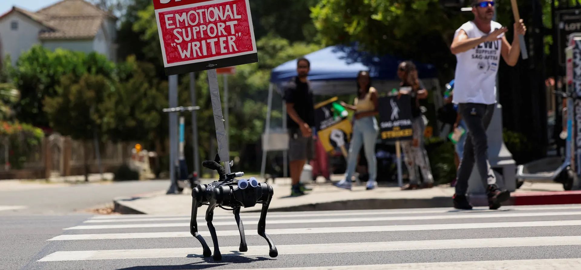 Los Ángeles, Estados Unidos. Un perro robot llamado Gato lleva un cartel como miembros del Gremio de Guionistas de América y el sindicato de actores SAG-AFTRA piquetes fuera de Paramount Studios durante una huelga. Fotografía: Mario Anzuoni/Reuters