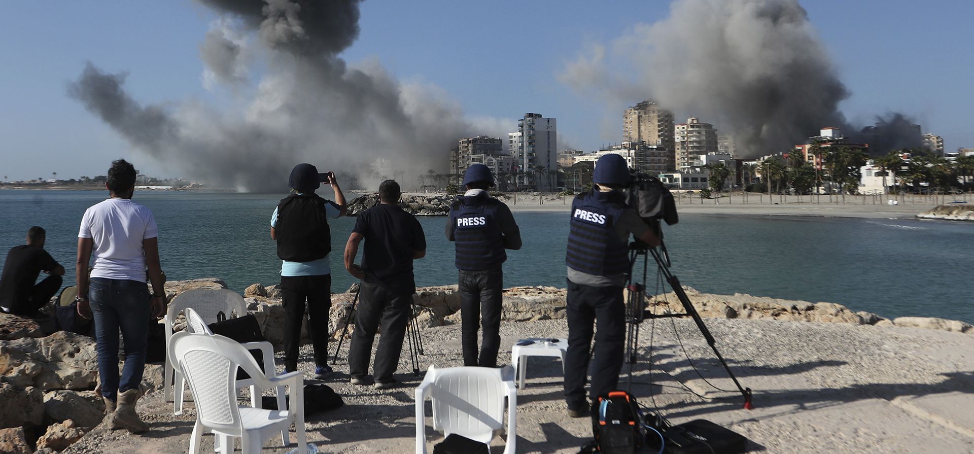 Periodistas filman mientras sale humo de los edificios alcanzados por los ataques aéreos israelíes en Tiro, en el sur del Líbano, el lunes 28 de octubre de 2024. (Foto AP/Mohammed Zaatari)