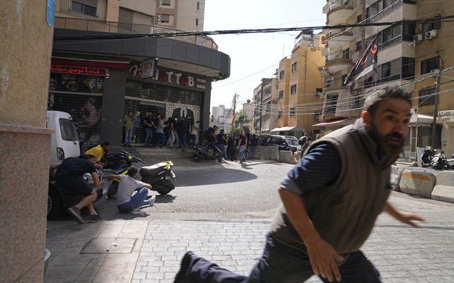 Un hombre corre para refugiarse de los partidarios del grupo chiíta, aliado con armas de fuego de Hezbolá, durante los enfrentamientos armados que estallaron durante una protesta en el suburbio de Dahiyeh, en el sur de Beirut, Líbano, el jueves 14 de octubre de 2021.