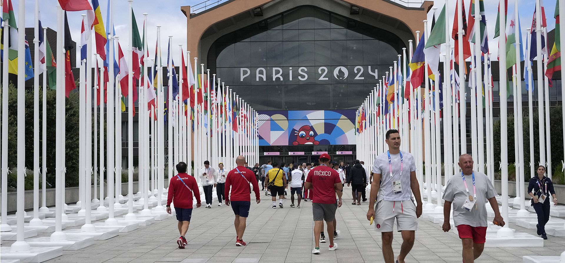 La gente camina frente a la cantina de la Villa Olímpica, en los Juegos Olímpicos de Verano de 2024, el lunes 22 de julio de 2024, en París, Francia. (Foto AP/Michel Euler, Piscina)
