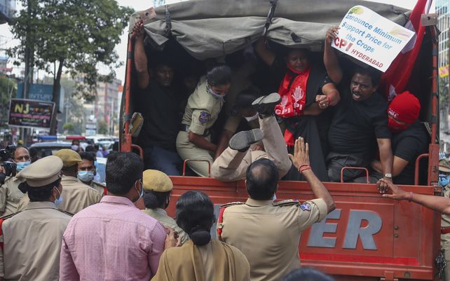 Una mujer policía se cae dentro de un camión mientras detiene a partidarios del Partido Comunista de la India (CPI) durante una protesta en la que se exige al gobierno central y a los gobiernos estatales que detengan la apropiación de la explotación de arroz del estado en Hyderabad