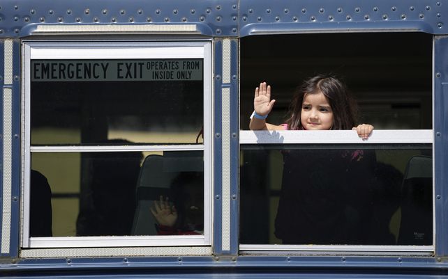 Niños afganos evacuados recientemente saludan desde un autobús en la base aérea estadounidense de Ramstein