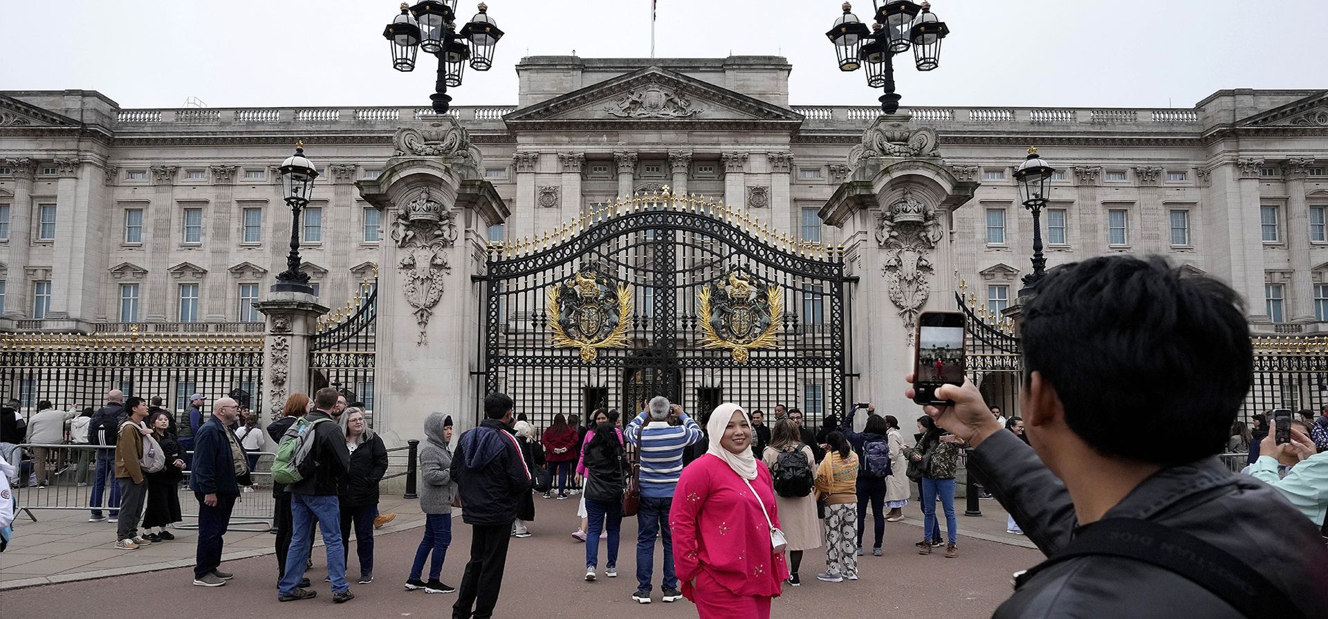 Turistas toman fotografías mientras visitan el Palacio de Buckingham en Londres, el miércoles 3 de mayo de 2023. La coronación del rey Carlos III se llevará a cabo en la Abadía de Westminster el 6 de mayo.  (Foto AP/Frank Augstein)