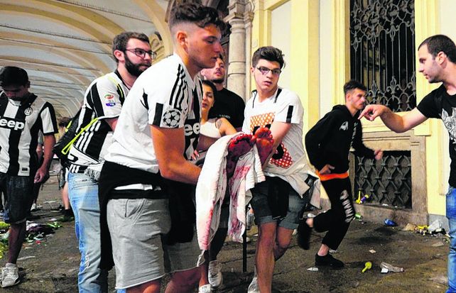 Pánico. Una simpatizante de Juventus herida es auxiliada por sus pares..